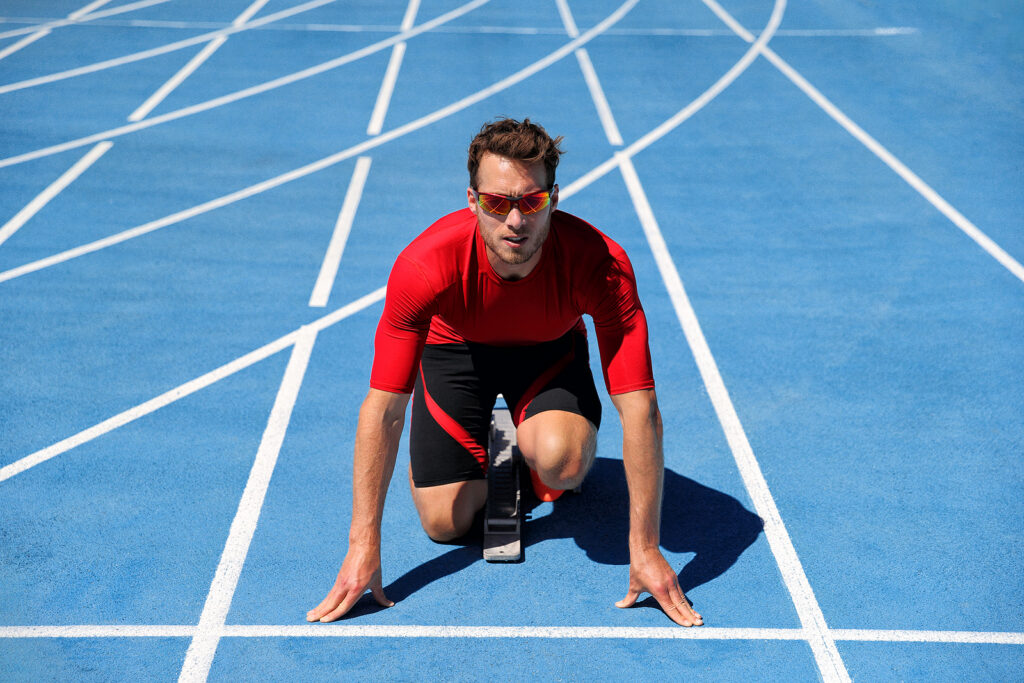 Runner athlete starting running at start of run track on blue ru