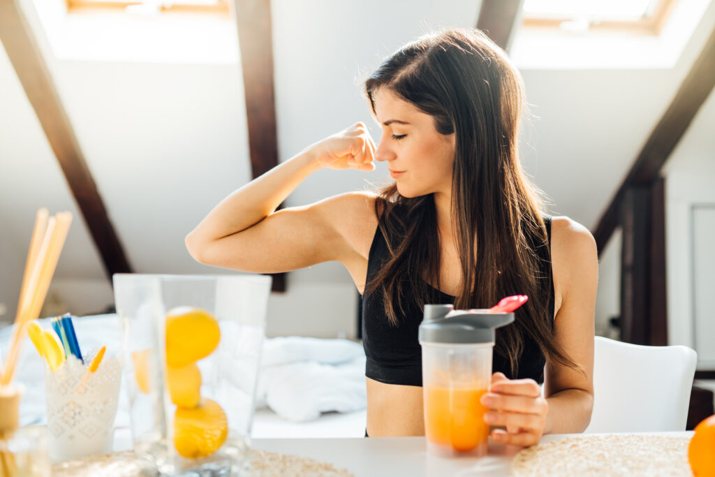 Woman At Home Drinking Orange Flavored Amino Acid Vitamin Powder
